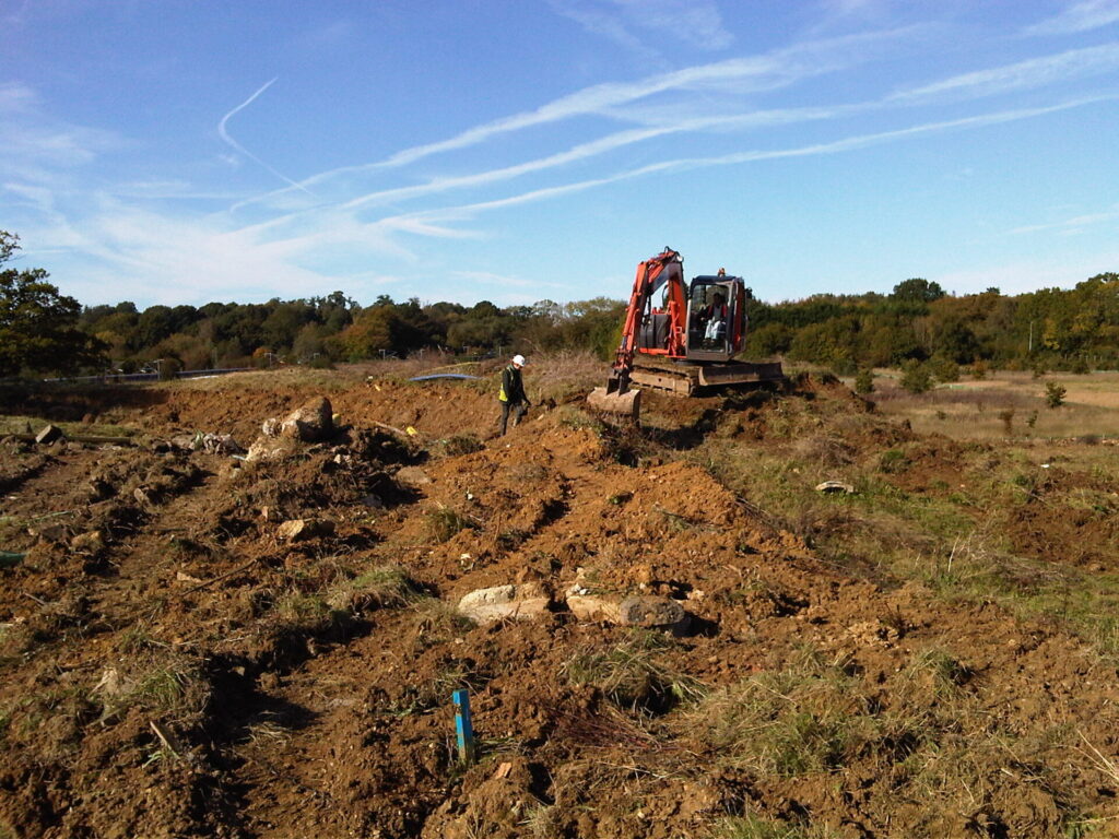 Worker and digging machinery on open land
